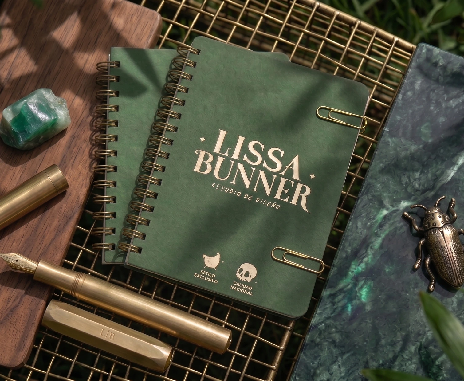 Libreta verde con el logo de Lissa Bunner y accesorios de escritorio.